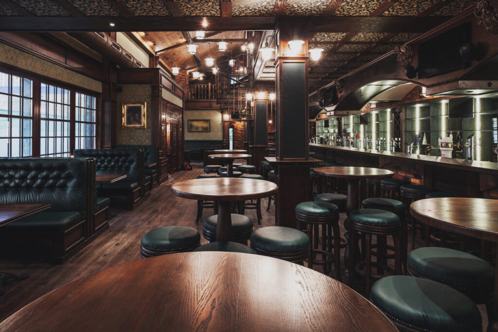 The interior of an old-fashioned bar with a lot of wood flooring and seating.