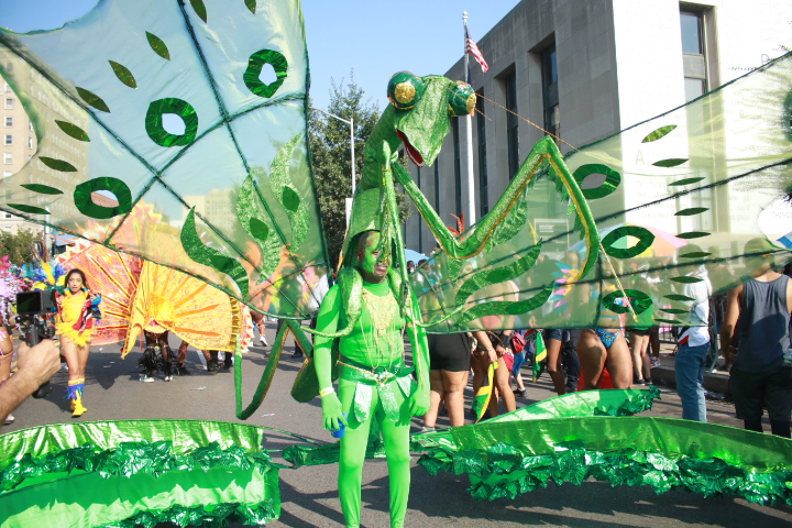 A man wears a massive, elaborate costume depicting a green praying mantis at the 2023 West Indian Day Parade.