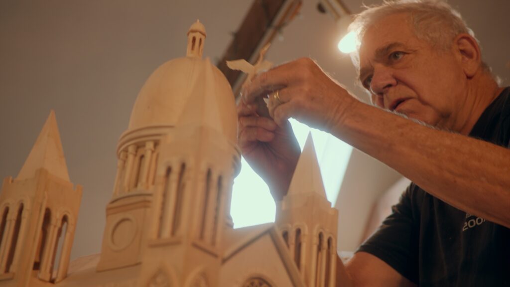Jim Grashow placing the finishing touch on his masterpiece a delicate bird, crowing the summit of his cathedral.