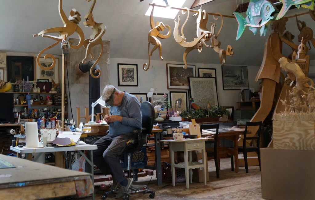 Jim is surrounded by a menagerie of his own making as he busily chips and carves away at his magnum opus. Jim shows that art is serious play.